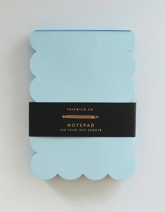 Light blue notepad with scalloped edges and black label on a white background