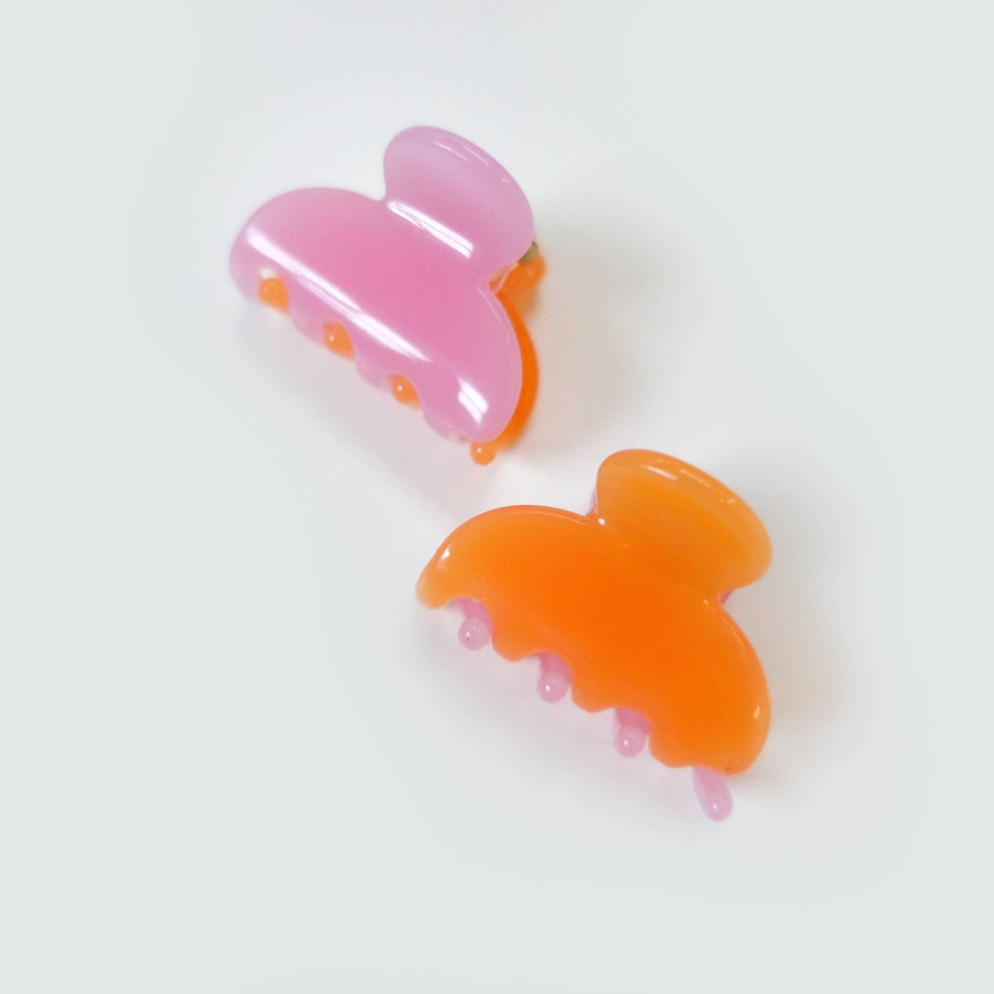 Set of two mini pink and orange semi-sheer jelly hair claw clips.