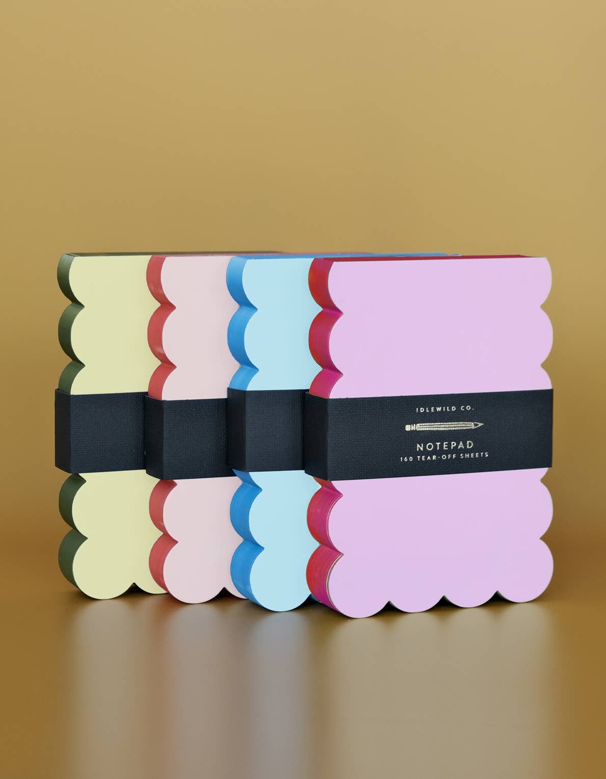 Set of colorful notebooks with scalloped edges on a beige background