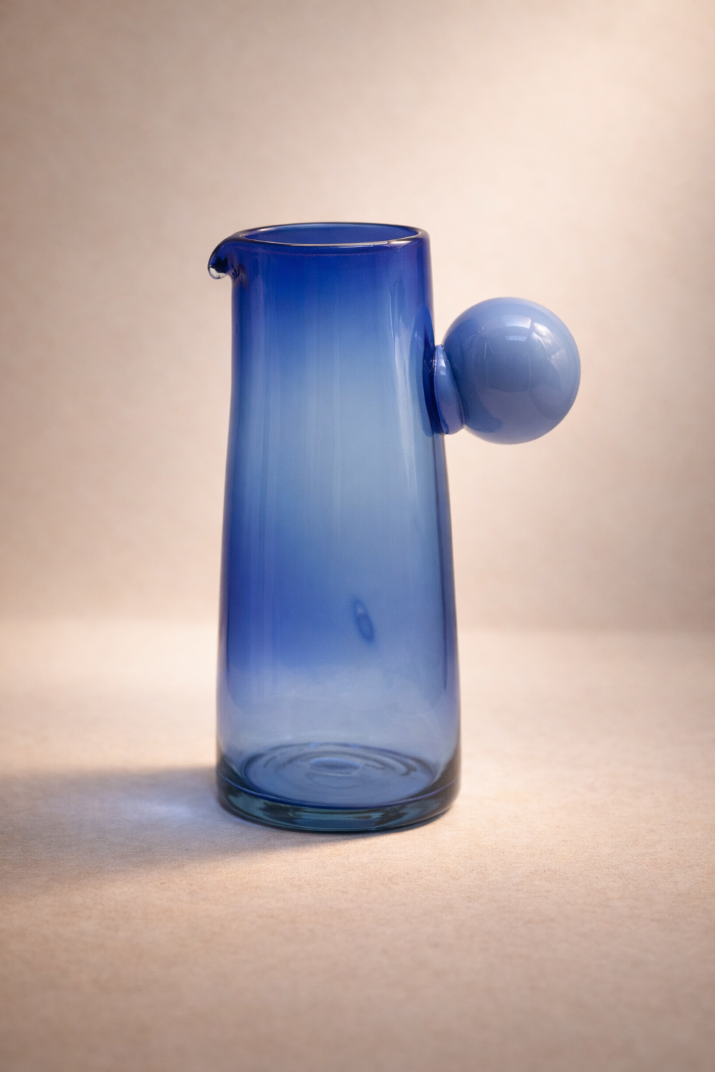 Cobalt blue mouth-blown recycled-glass pitcher standing upright against a plain background.