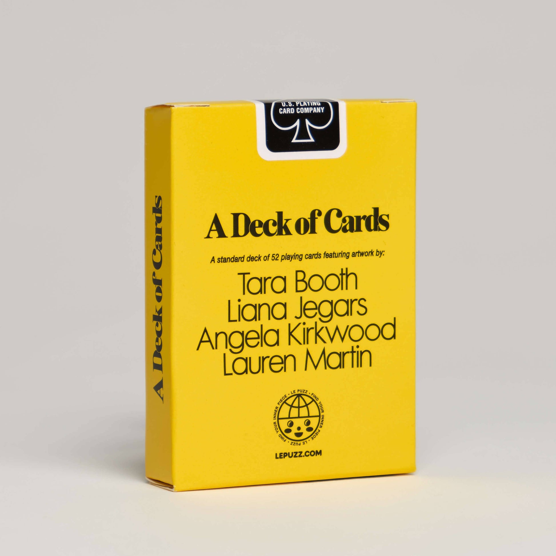 Yellow box of playing cards with black text on the backside of the box with a gray background