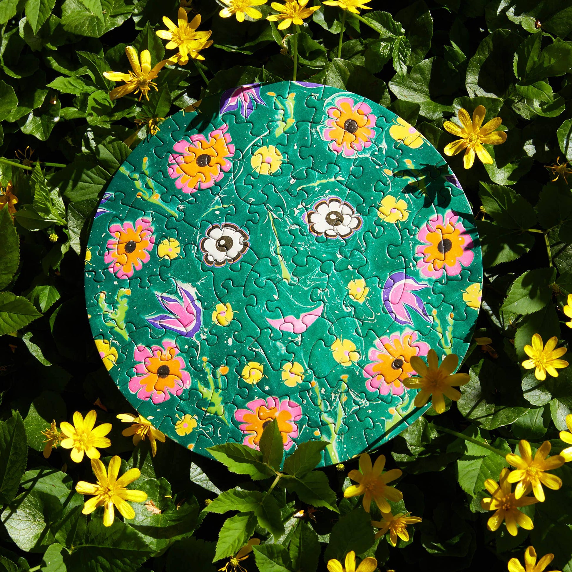 Round puzzle with a floral design on a bed of green leaves and yellow flowers