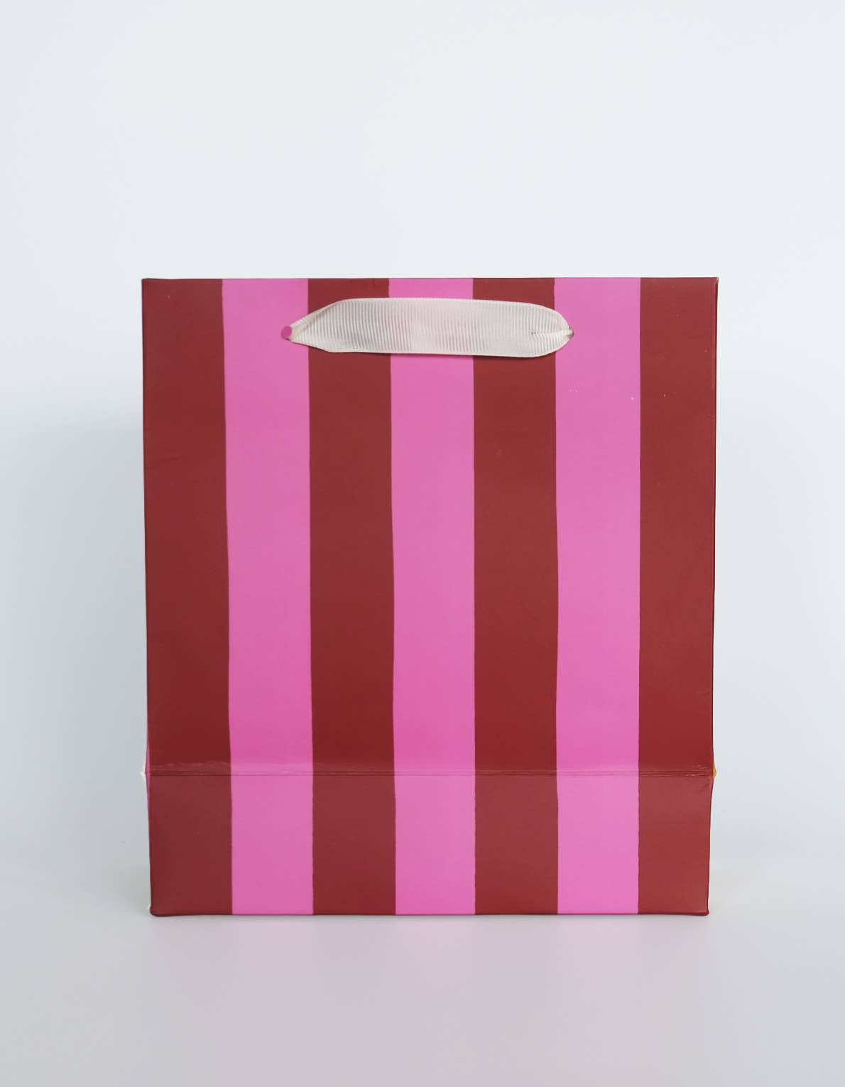 Striped paper bag with pink and red vertical stripes on a white background