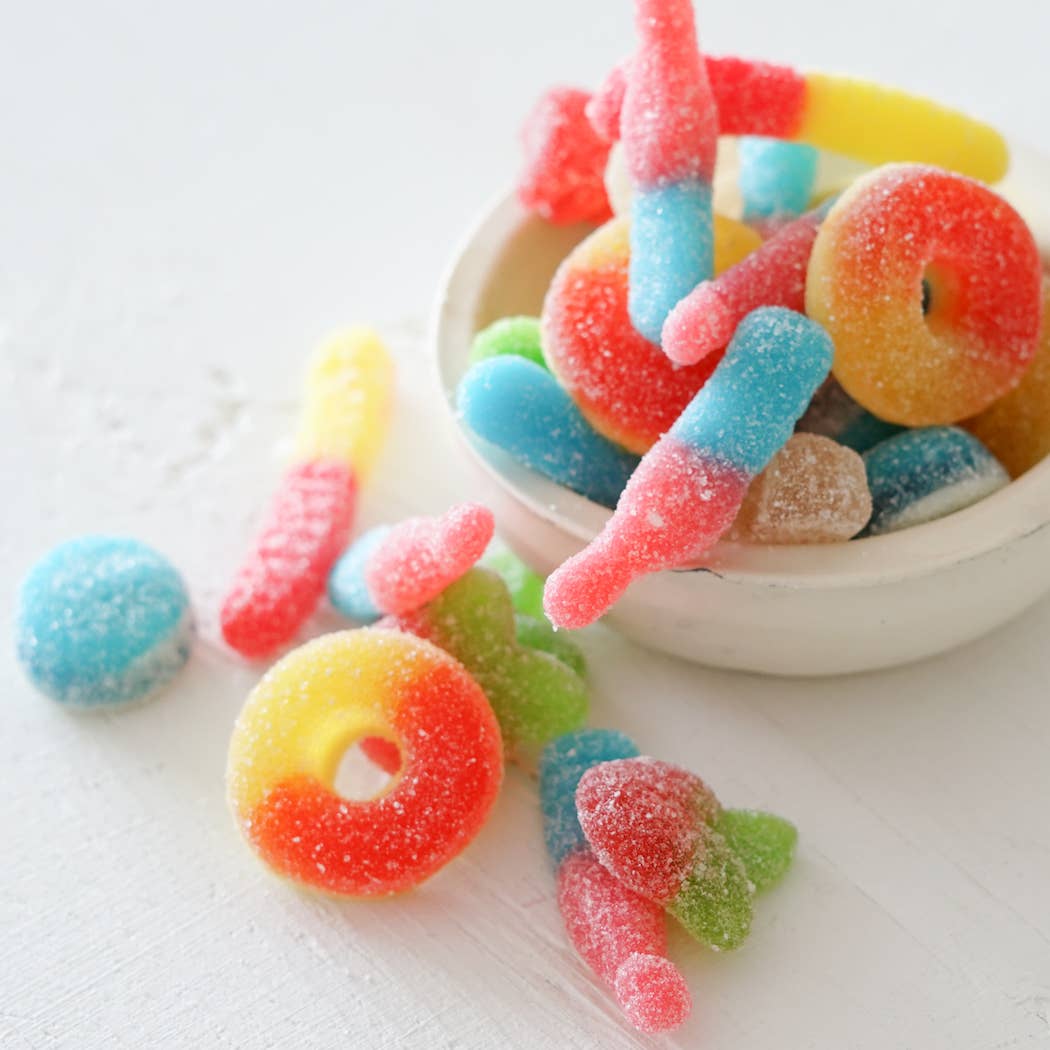 Colorful gummy candies in a white bowl on a light background