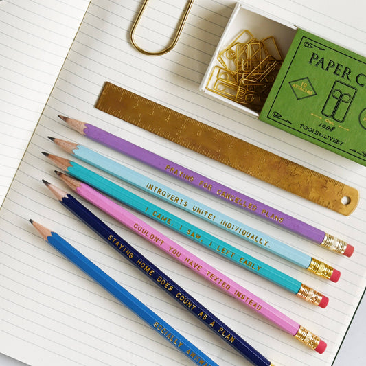 Colorful pencils with inspirational quotes on a notebook with a ruler and paper clips.