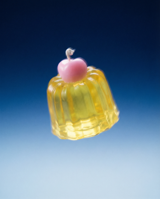 Chemistry yellow Canele jelly candle with a pink cherry on top, front view.