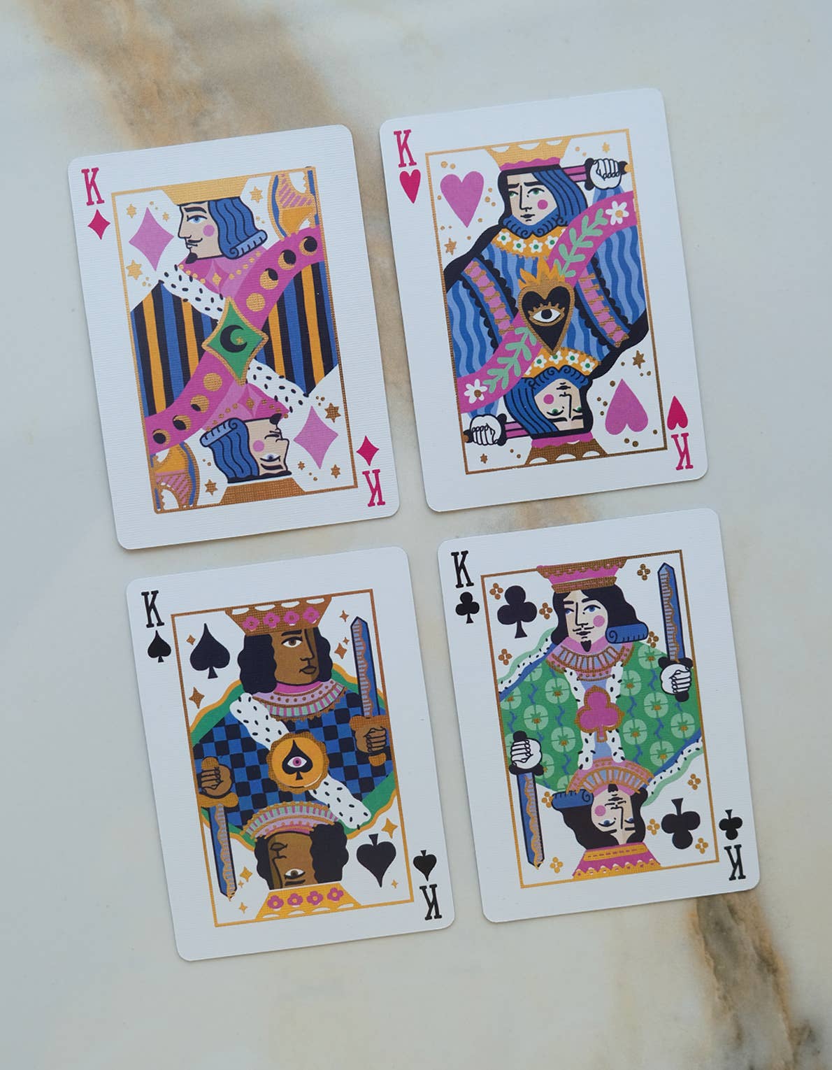 Four playing cards with colorful designs on a light background