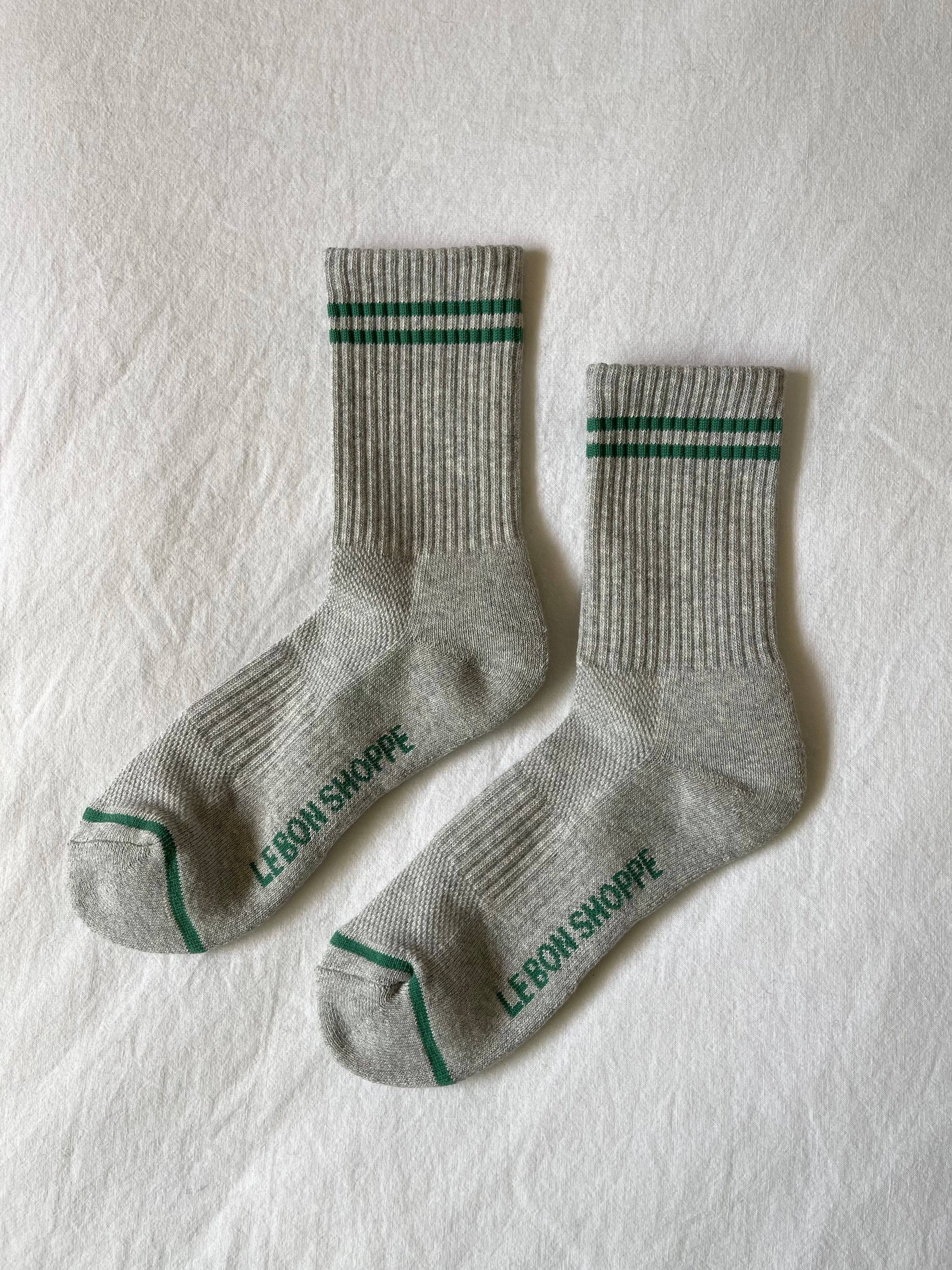 Two gray socks with green accents on a light textured surface