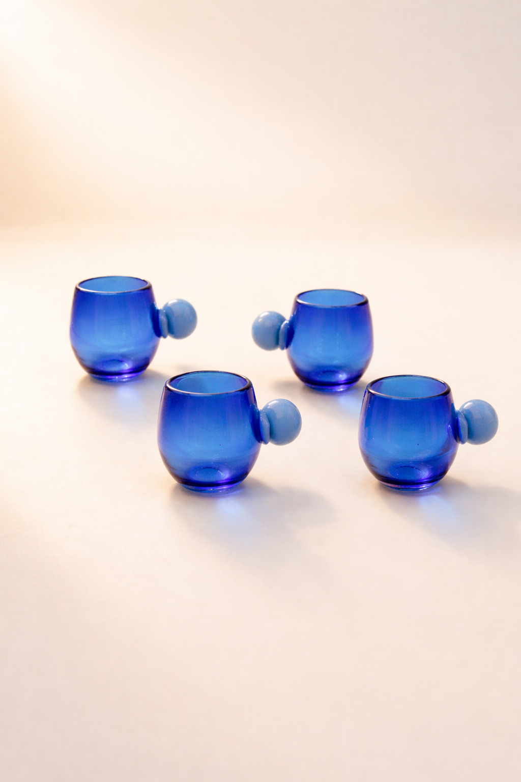 Three short glasses in recycled blue glass, grouped on a plain background.