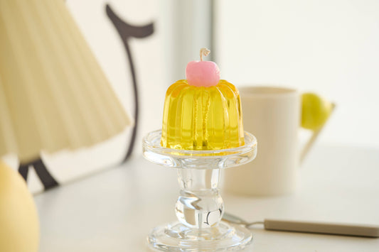 Another view of the yellow Canele candle topped with a pink cherry.