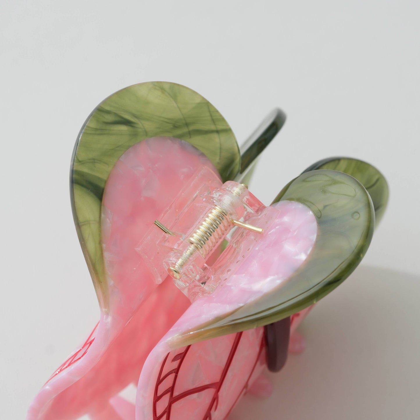 Pink and green anthurium-flower claw clip with a clear center on a light gray background