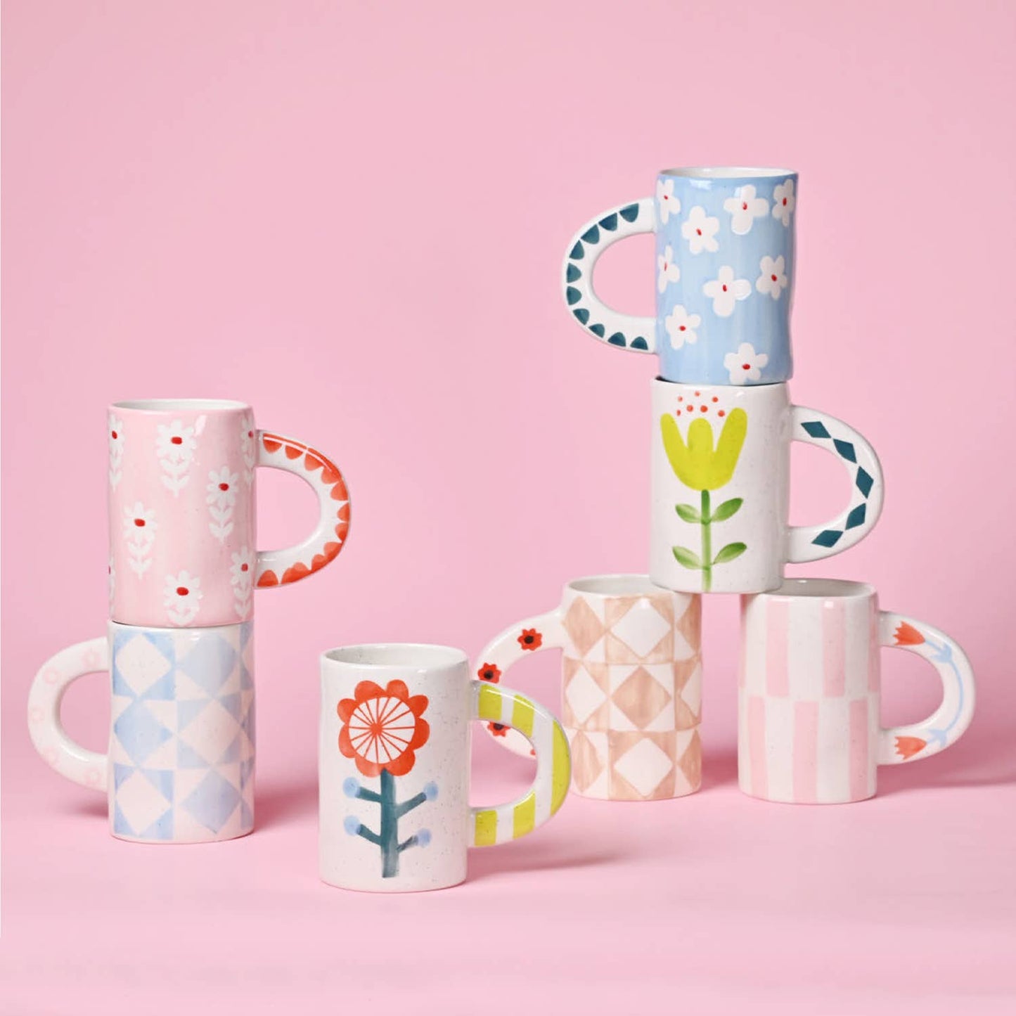 Set of colorful patterned mugs on a pink background