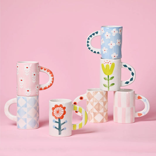 Set of colorful patterned mugs on a pink background