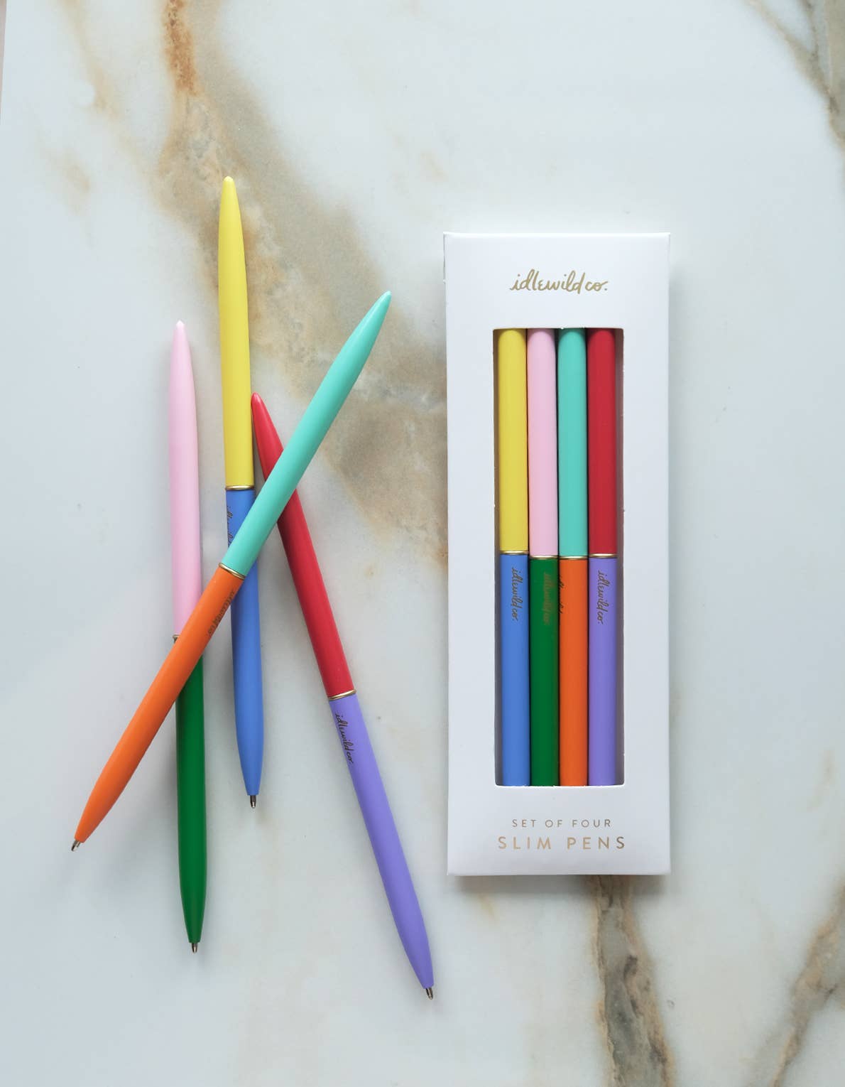 Set of colorful pens with a packaging box on a marble surface