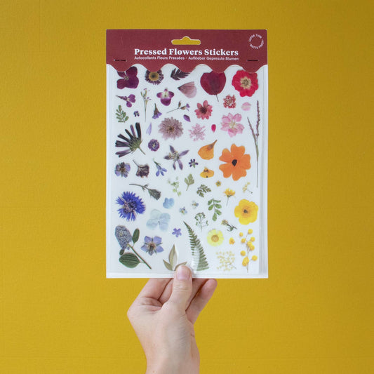 Sheet of pressed flowers stickers held against a yellow background