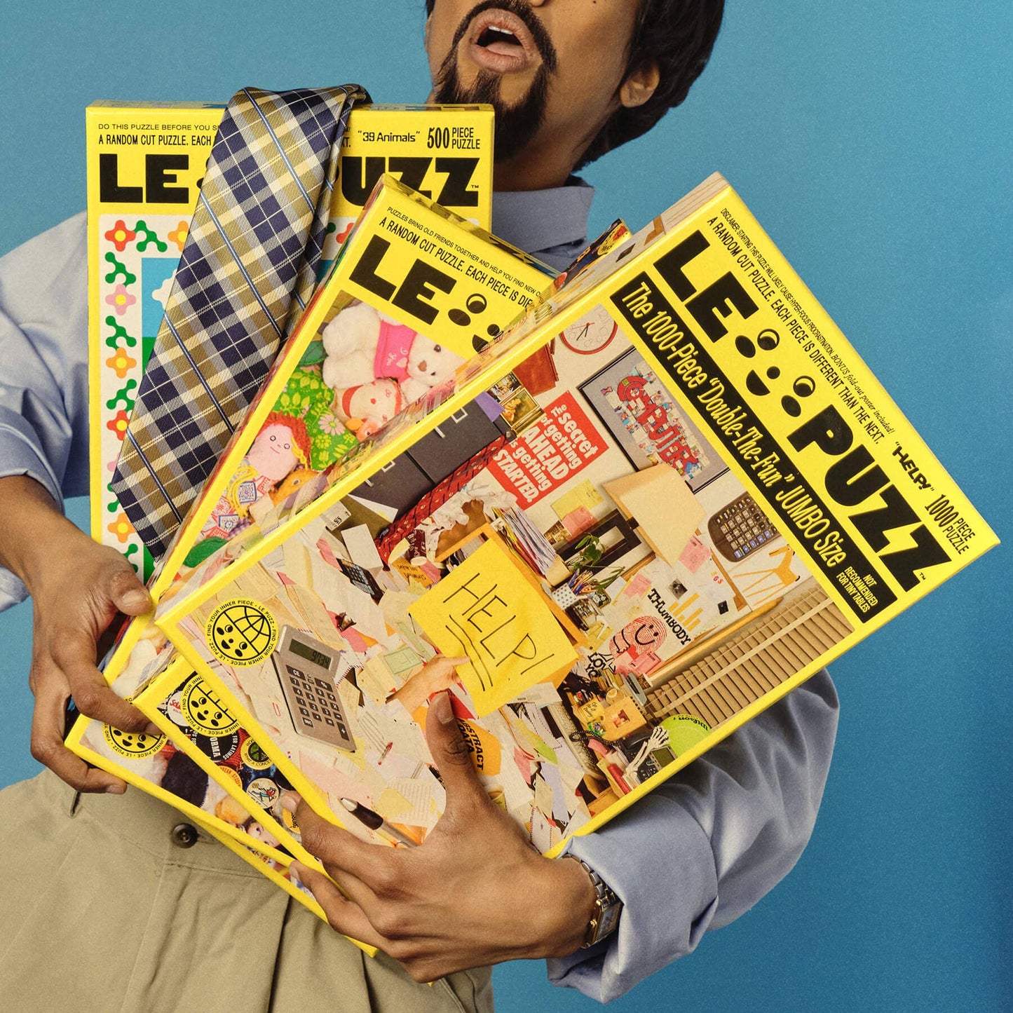 Person holding three colorful puzzle boxes with visible branding against a blue background