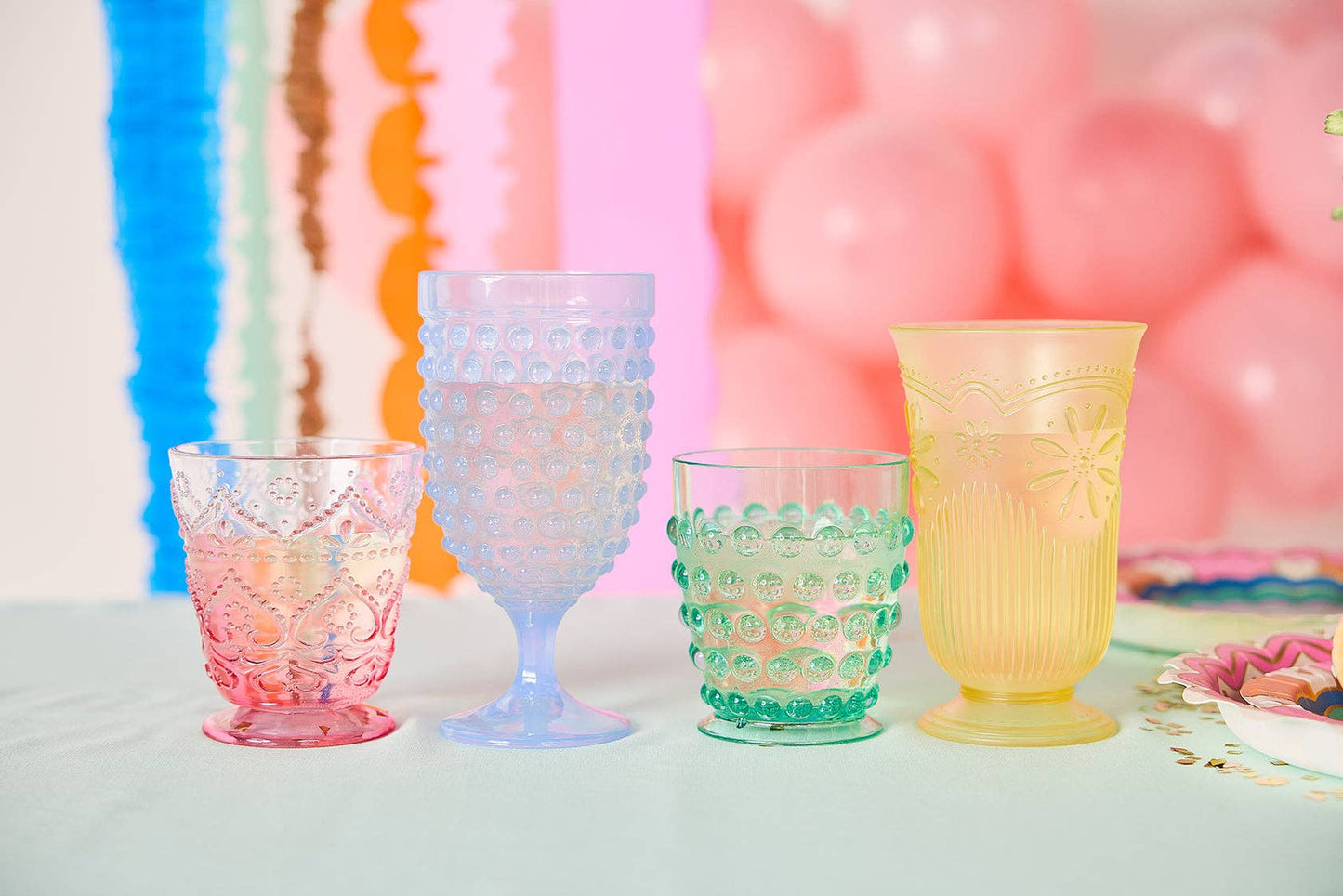 Set of four pastel vintage-style plastic cups in blue, pink, green, and yellow.