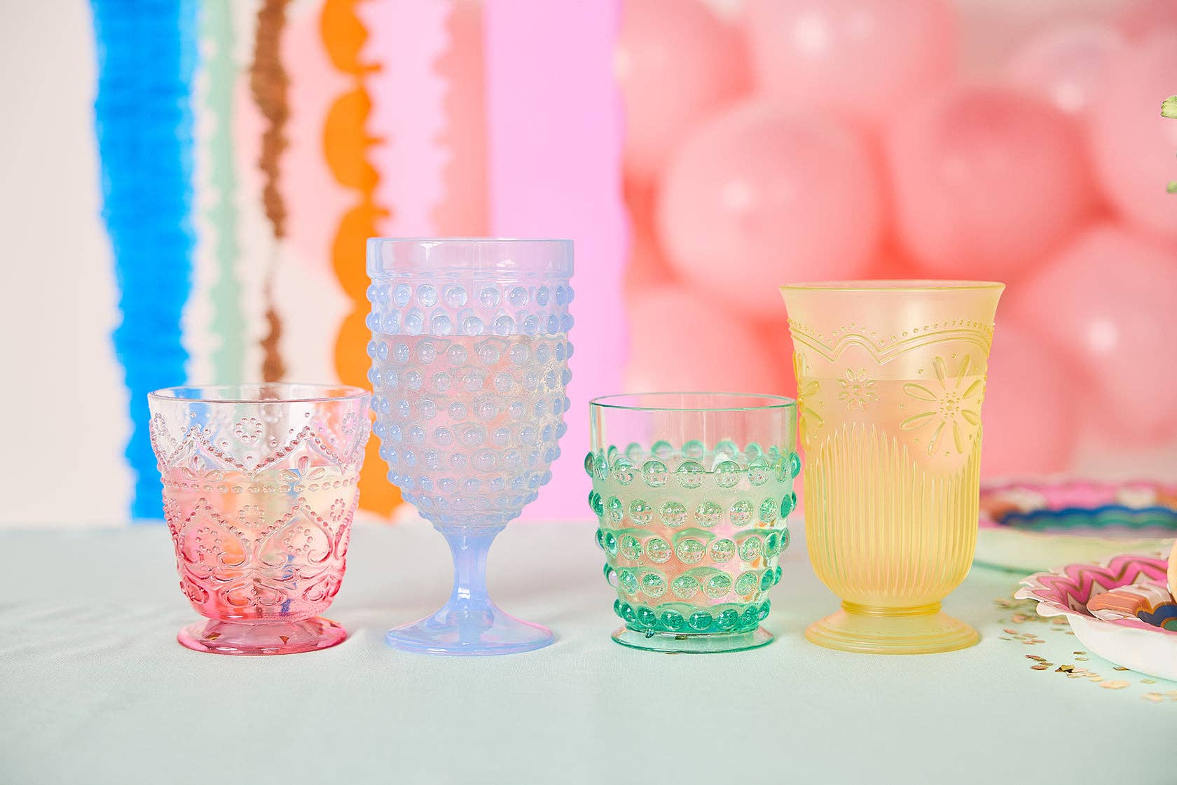 Set of four pastel vintage-style plastic cups in blue, pink, green, and yellow.