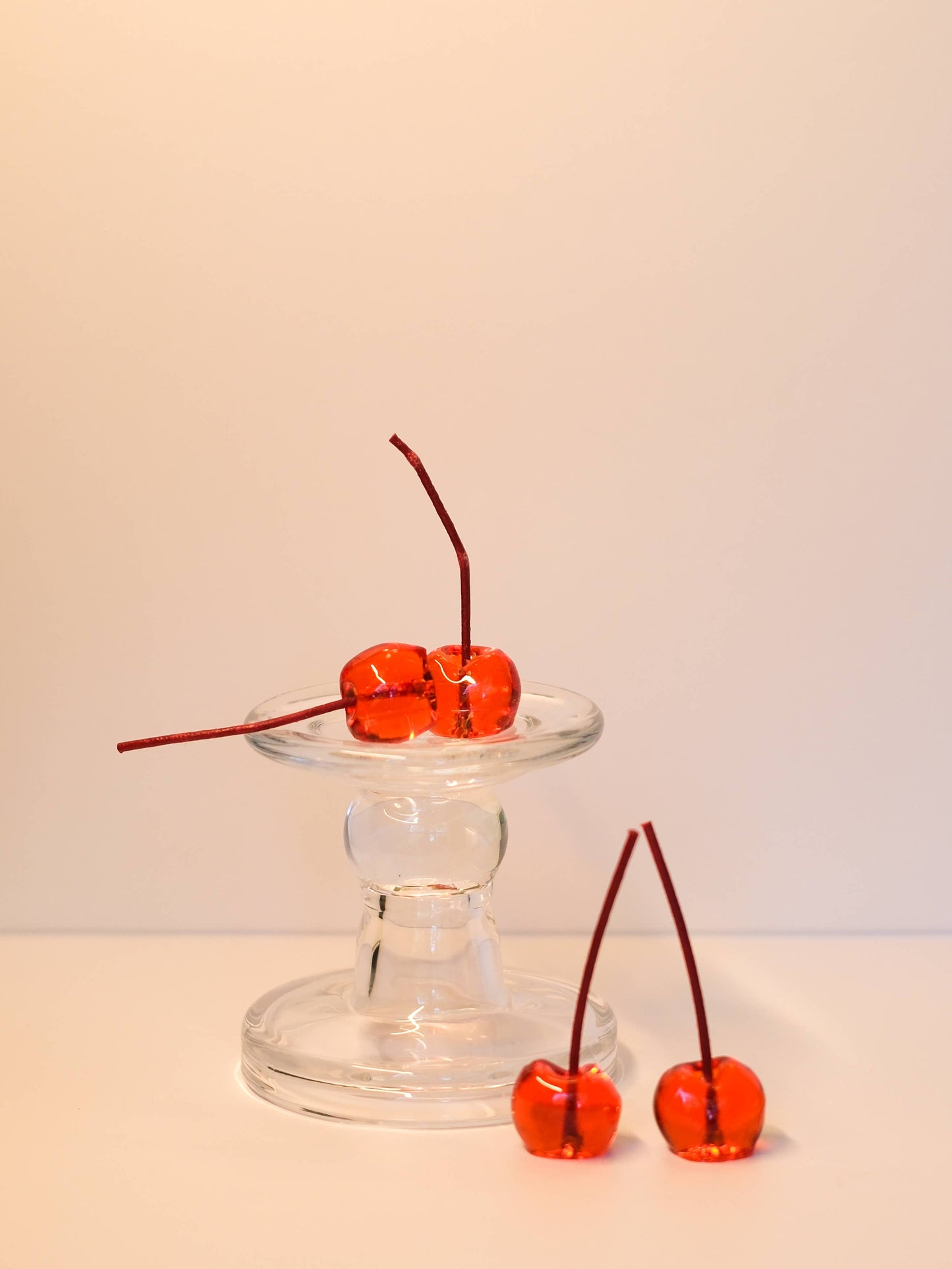 A single cherry-shaped jelly candle with its slender stem.