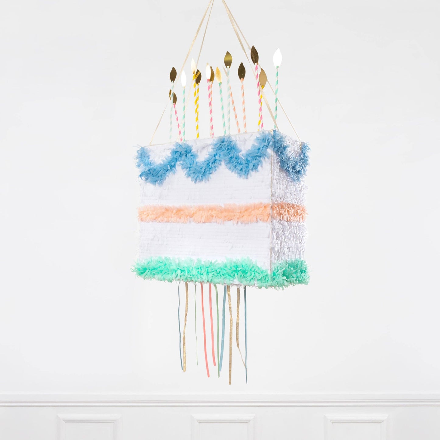 Peach, blue, and mint tissue-paper cake piñata with paper-straw candles