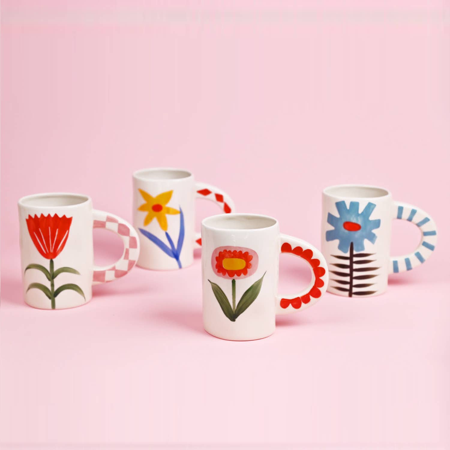 Set of four mugs with floral designs on a pink background