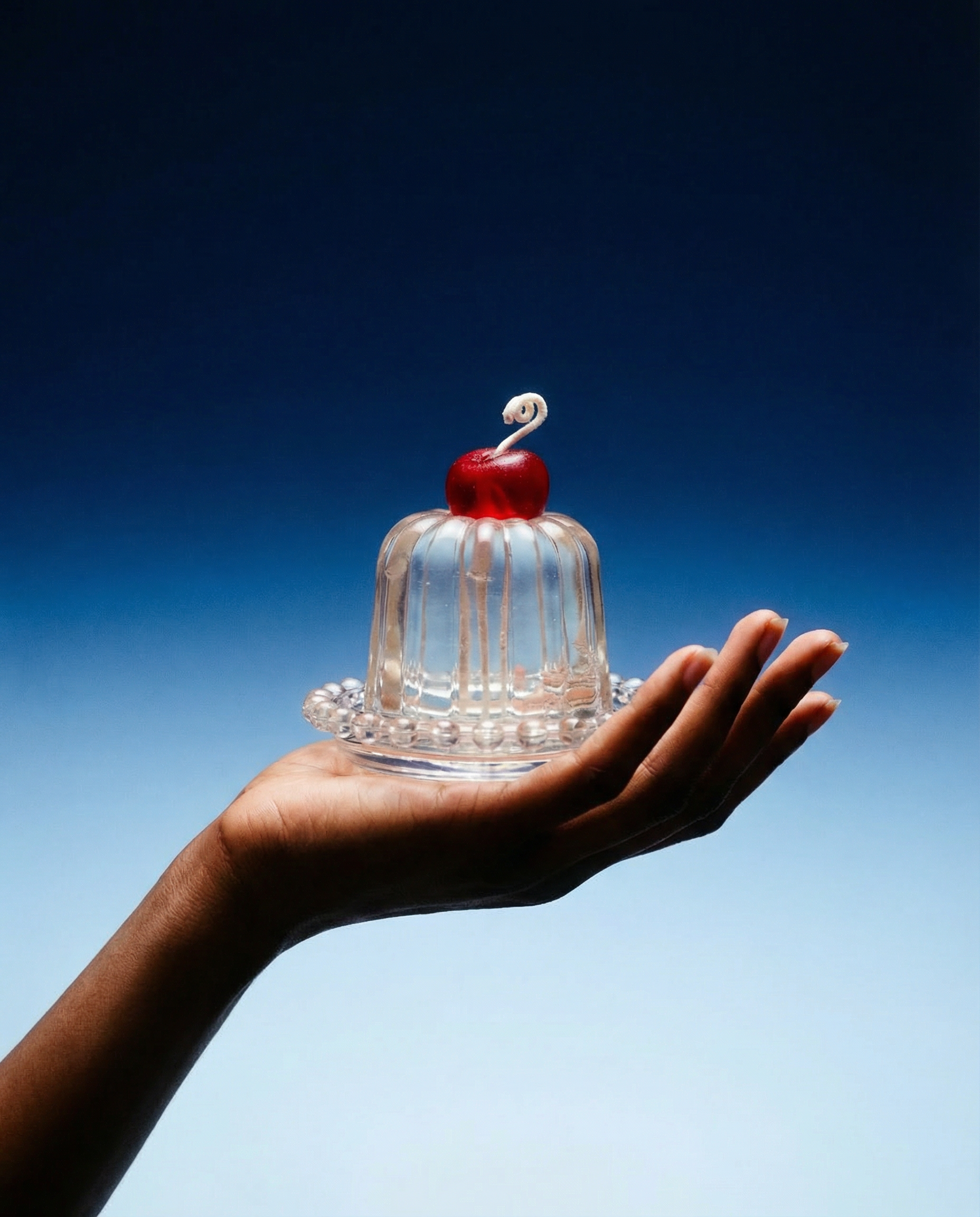 Insight clear Canele-shaped jelly candle with a red cherry on top, front view.
