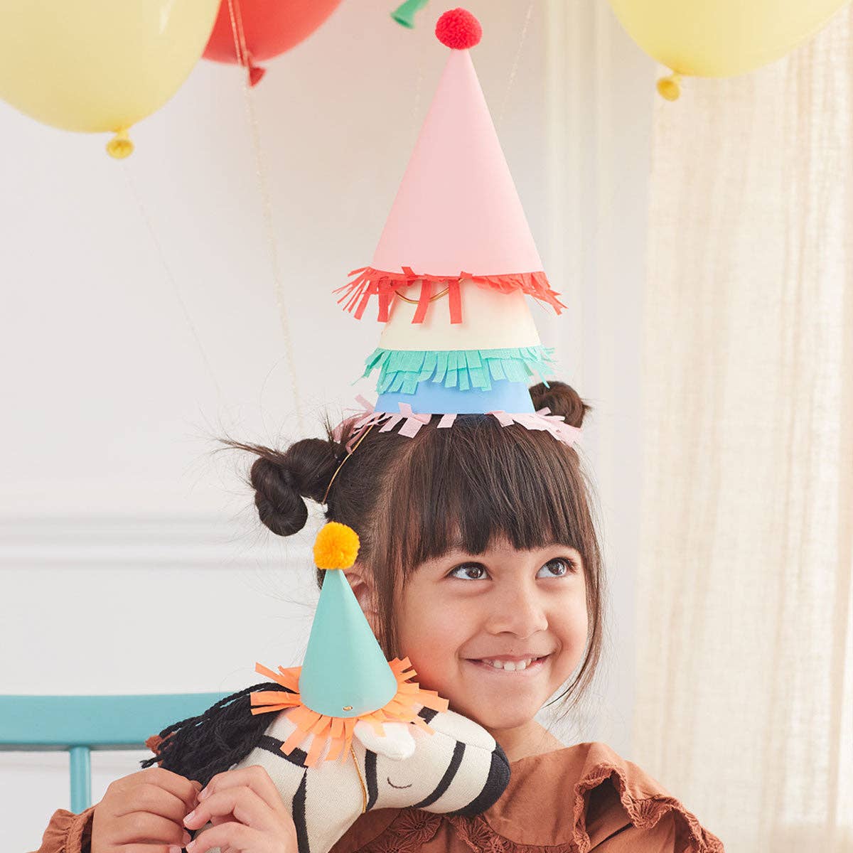 Mini party hat topped with a pompom above crepe paper fringing