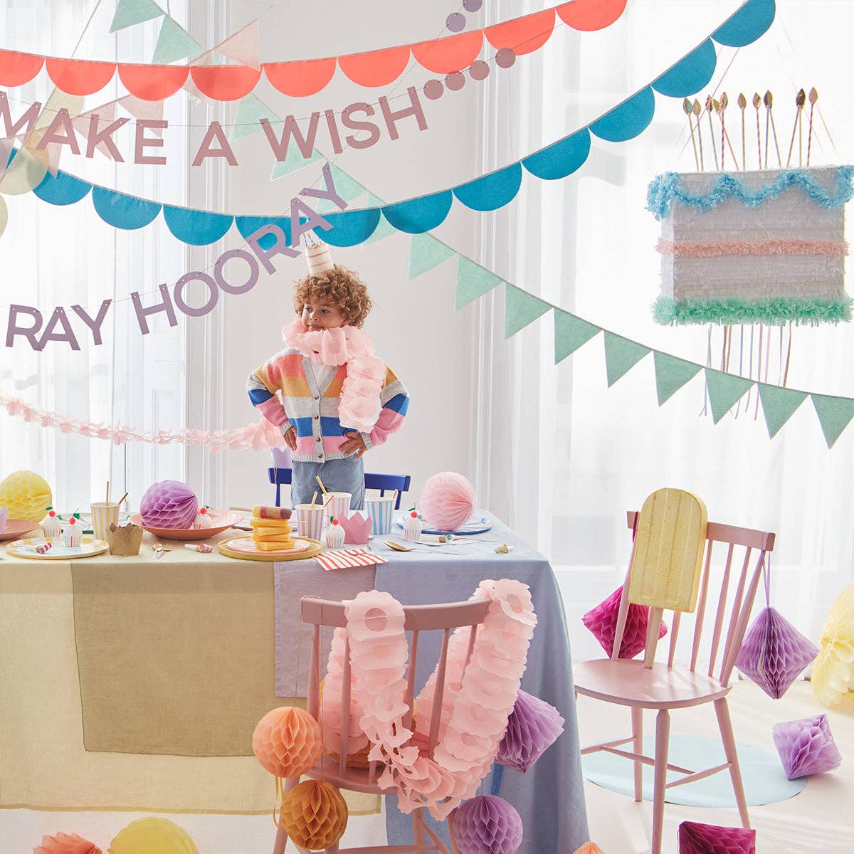 Cake piñata showing its blue, pink, mint, and gold pull ribbons