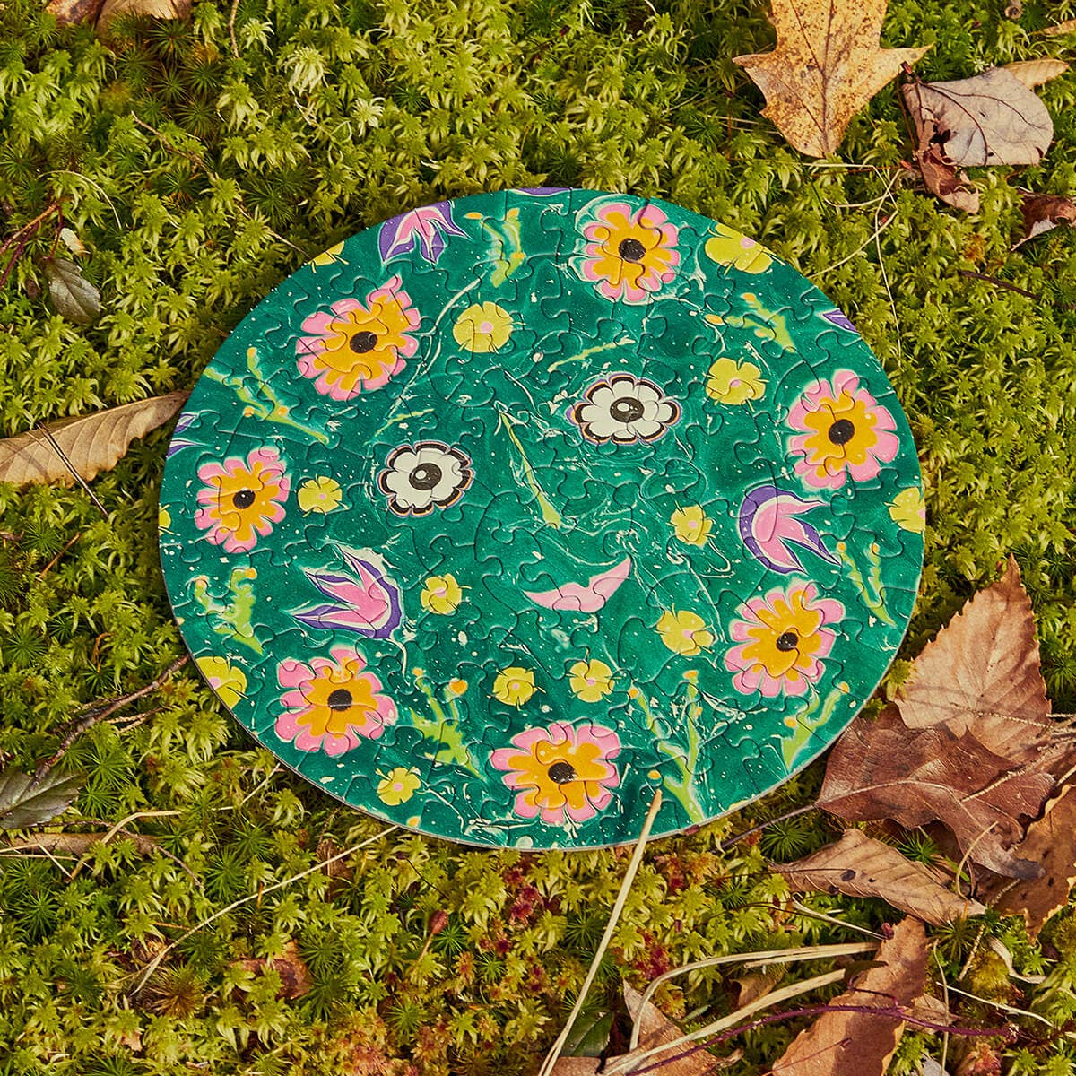 Round puzzle laid down in nature on a green leafy background