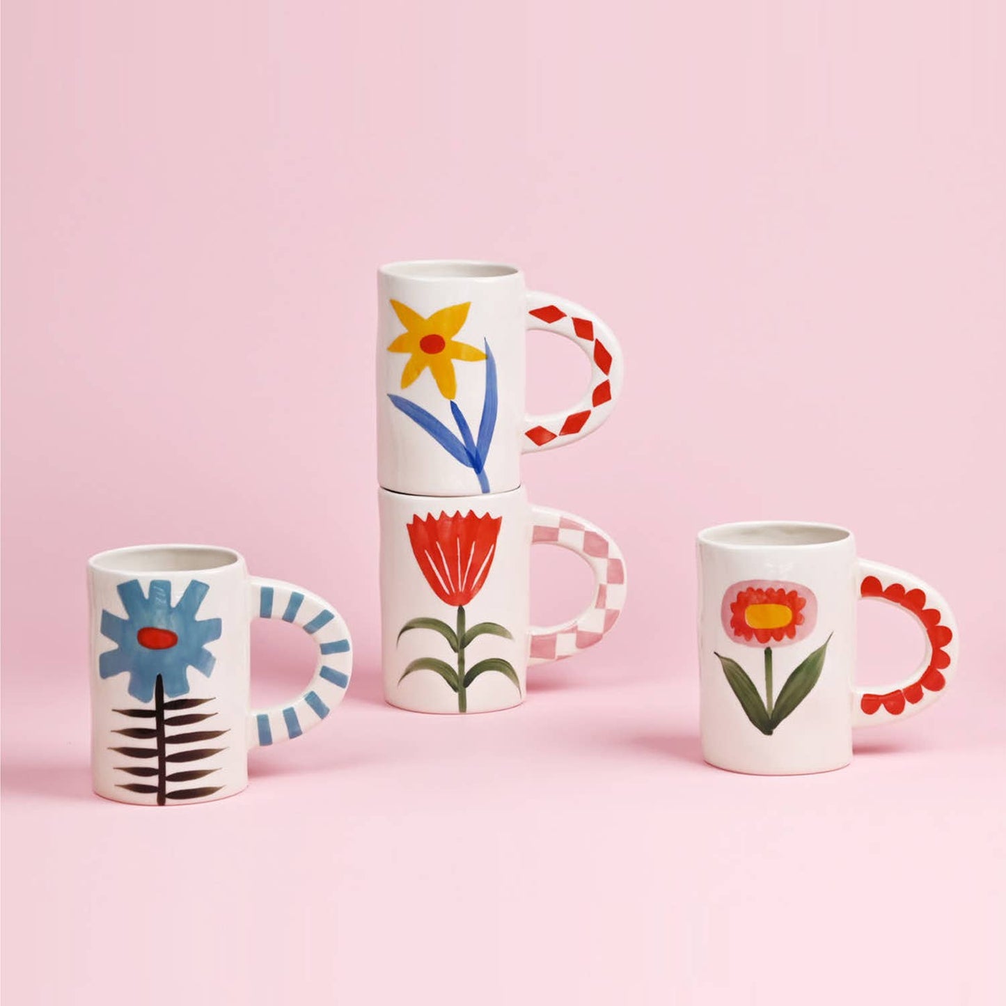 Set of four  ceramic mugs with floral designs on a pink background