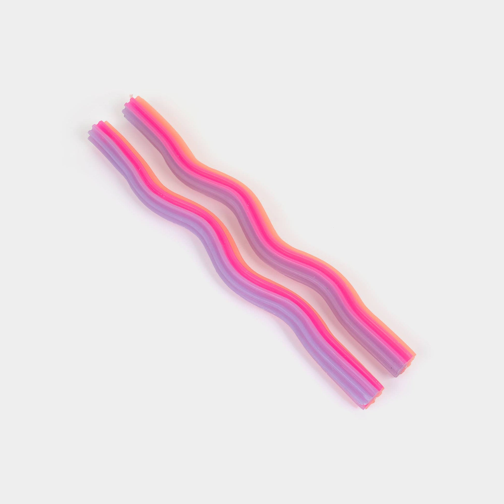 Orange, pink and lavender wiggle taper candles showing their undulating wave shape