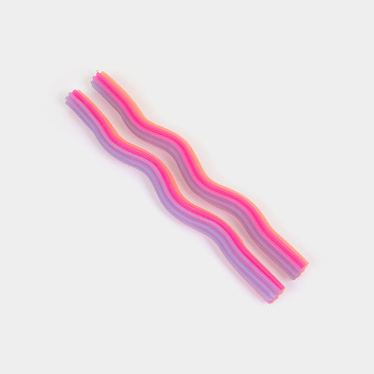 Orange, pink and lavender wiggle taper candles showing their undulating wave shape