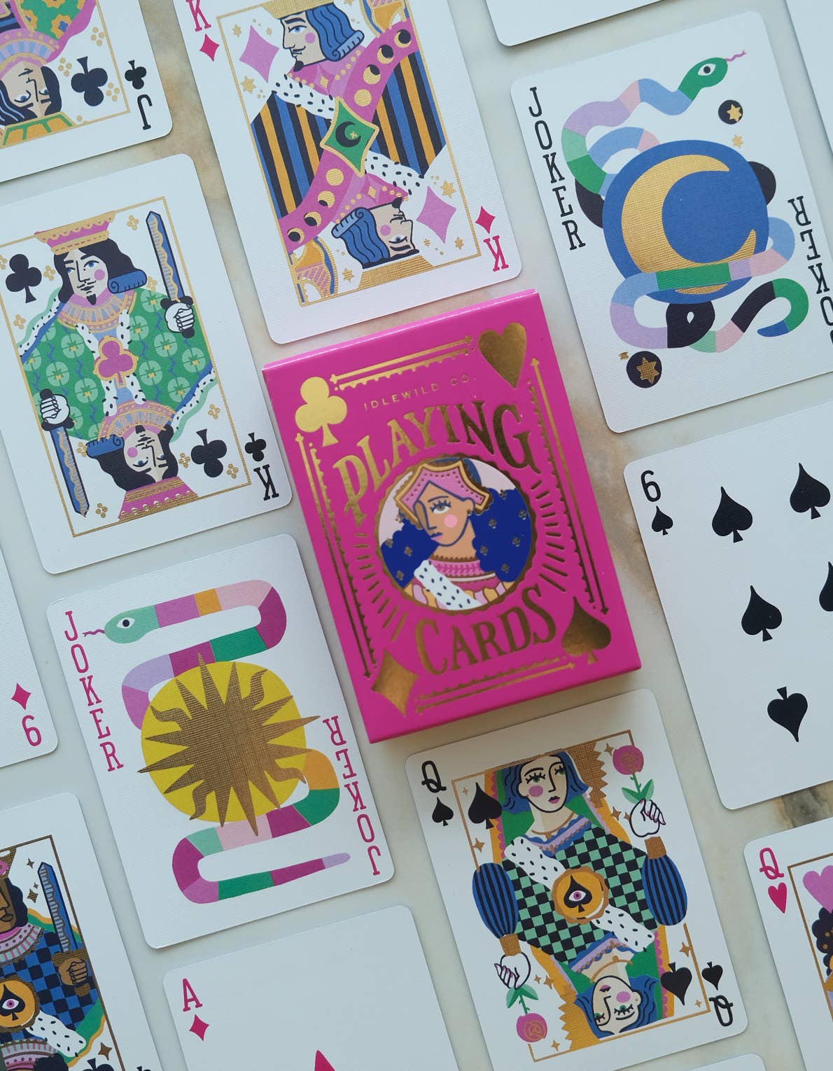 Colorful playing cards with a pink box labeled 'Playing Cards' on white surface.