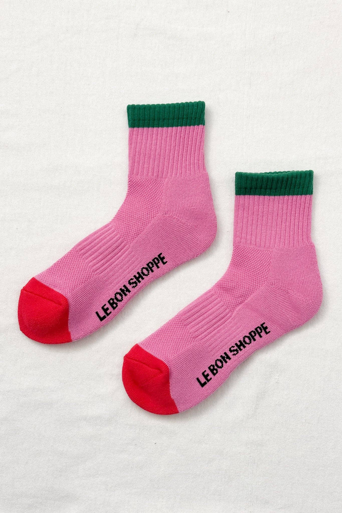 Pink socks with green and red accents on a white background