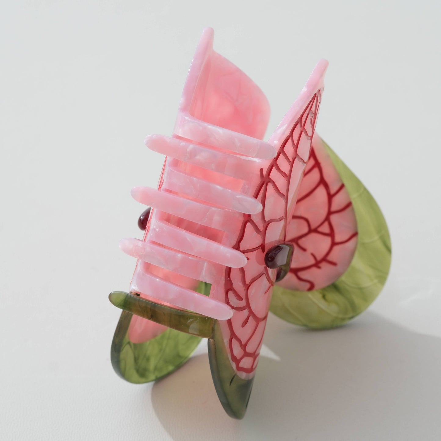 Pink and green anthurium-flower claw clip against a white background